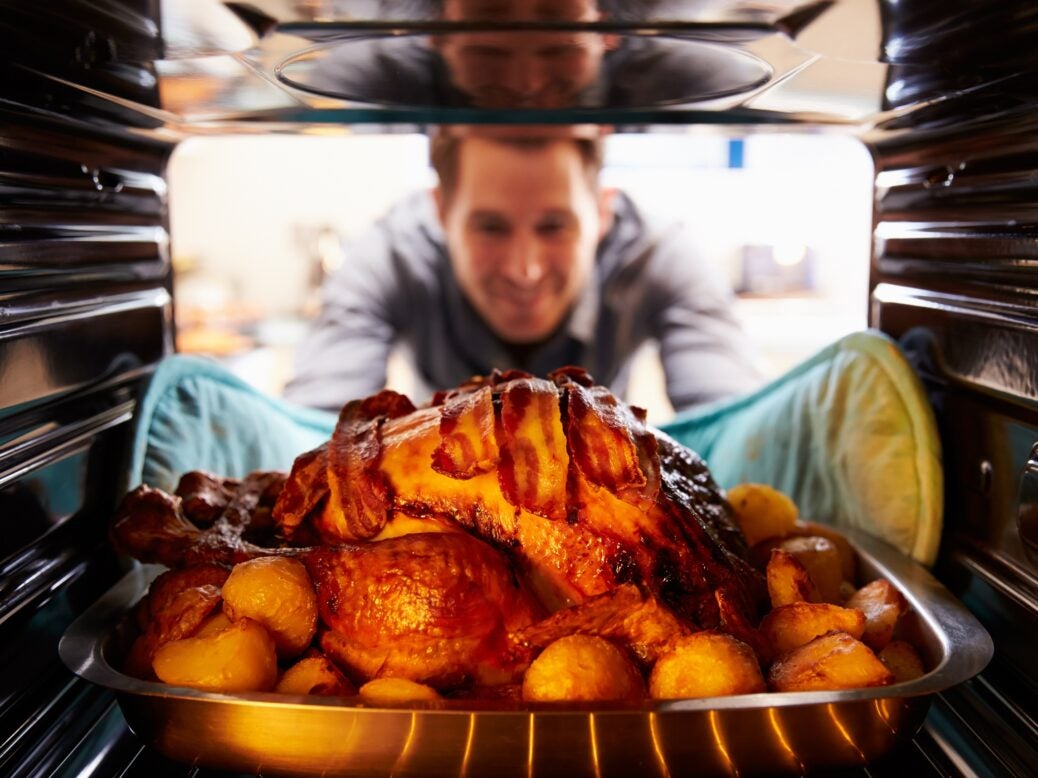 Man taking roast turkey out of oven
