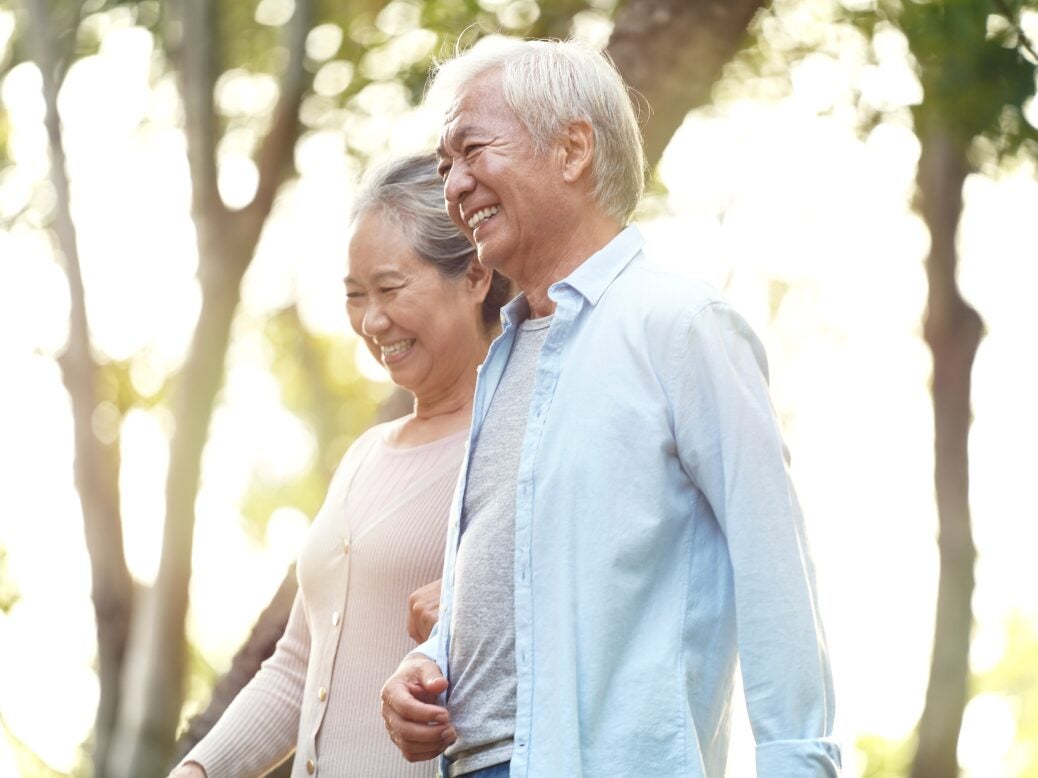 Happy, senior Asian couple walking outdoors in park