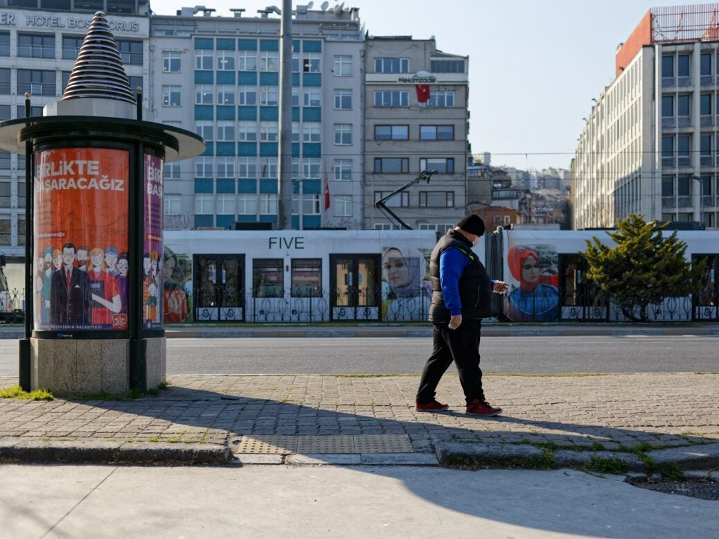 Man wearing face mask and plastic gloves because of coronavirus threat, walking on the street, Kabatas, Istanbul, Turkey, 13 April 2020