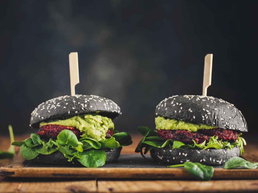 Two black-bun vegan burgers on a chopping board