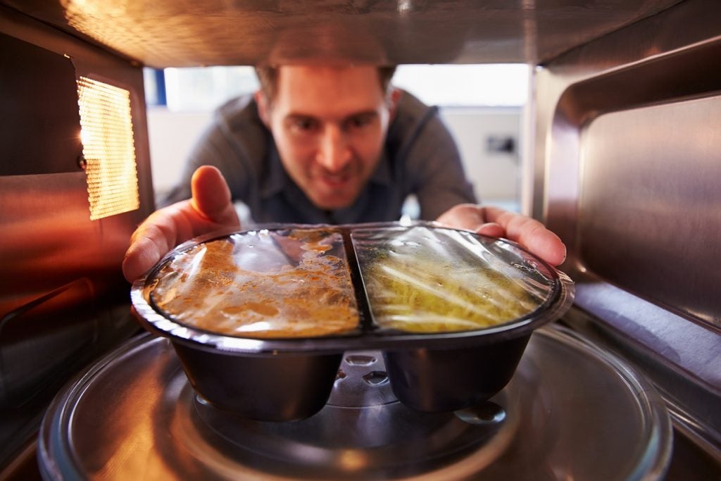 Generic image of man putting ready-meal into microwave to cook