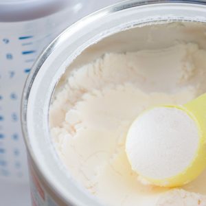 Milk powder for baby in measuring spoon on can.