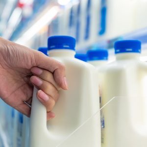Close up of asian woman shopper selecting pasteurized fresh milk and dairy products at the supermarket shelf, Shopping concept.