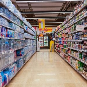 A brightly lit grocery store aisle stocked with bottled water and alcoholic beverages.